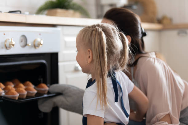 istock Excited little girl take ready muffins from oven 1204066383