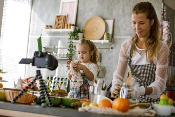 istock Mother and daughter making cookies and filming a video tutorial for it 1204066521