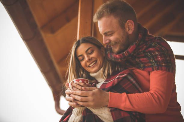 istock Couple warming their hands on a hot cup of tea while relaxing outdoors in the winter 1204067900