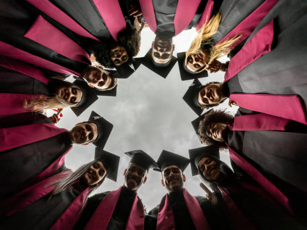 Group of graduating students in a circle on graduation day wearing their gowns and mortarboard