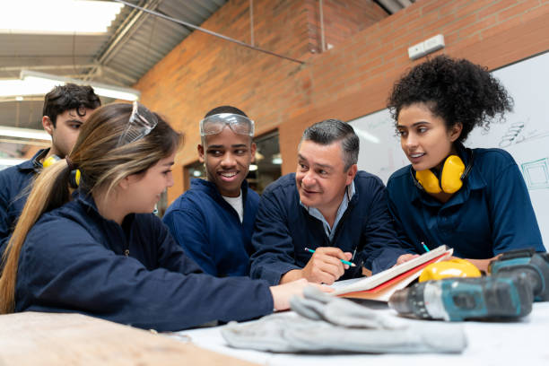 istock Group of students talking to their teacher in a manufacturing class 1204070513