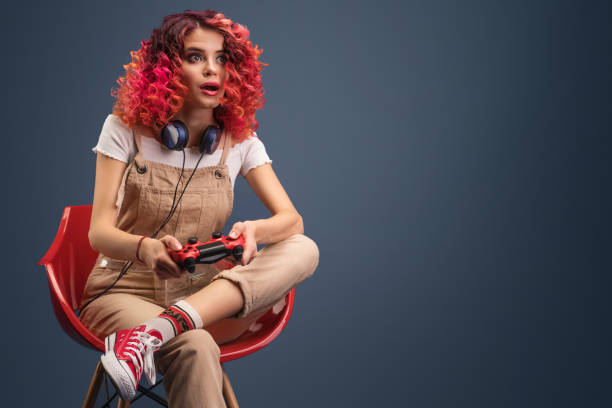 młoda kobieta z jasnoczerwonymi włosami cyrly gra w gry wideo. - video game joystick leisure games control zdjęcia i obrazy z banku zdjęć