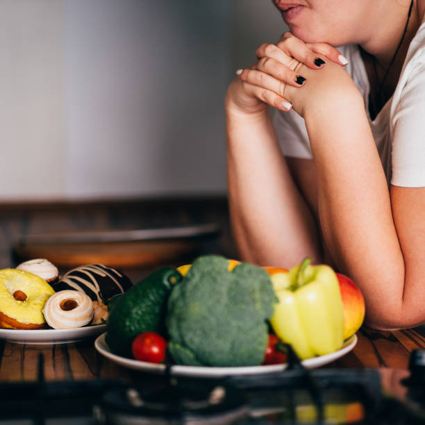 istock Woman choosing between sweets and healthy food 1204077132