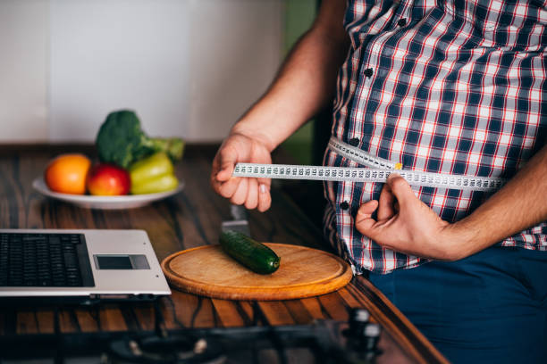 избыточный вес человек блоггер записи видео в своей кухне - instrument of measurement vegetable measuring exercising стоковые фото и изображения