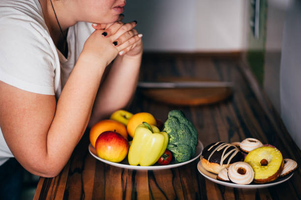 istock Woman choosing between sweets and healthy food 1204077301