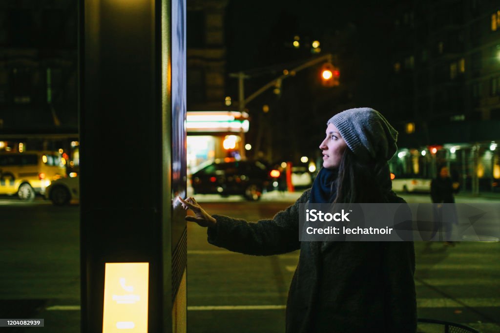 Woman using touch screen city display Young woman using interactive touch screen city display to check for information, New York City, USA. Billboard Stock Photo