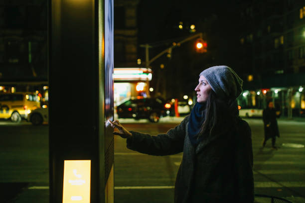 Woman using touch screen city display Young woman using interactive touch screen city display to check for information, New York City, USA. commercial sign stock pictures, royalty-free photos & images