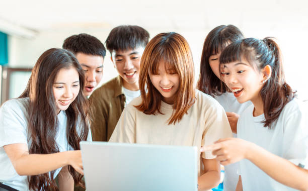 istock excited college students looking at laptop  in classroom 1204083244