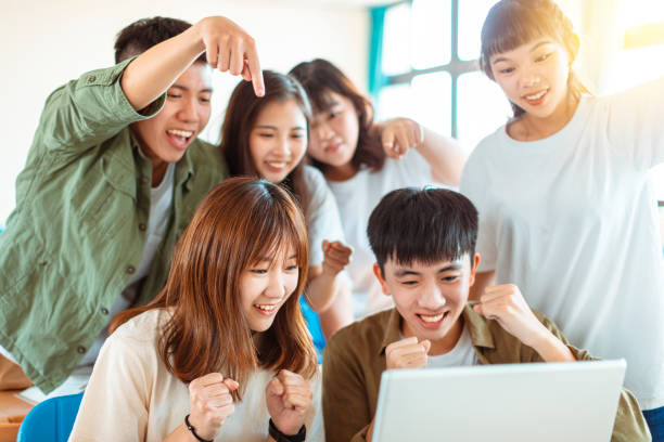 istock excited college students looking at laptop  in classroom 1204083246