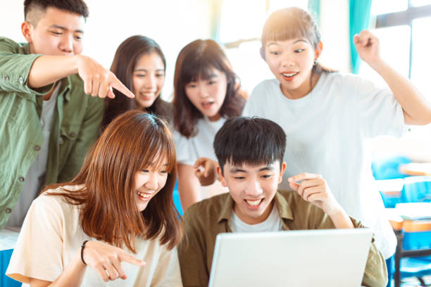 istock excited college students looking at laptop  in classroom 1204083256