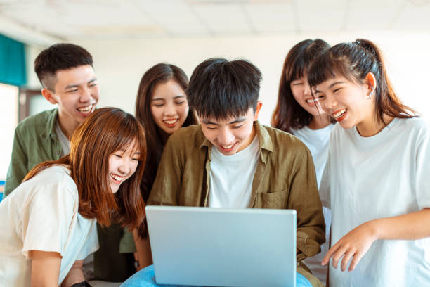 istock excited college students looking at laptop  in classroom 1204084468