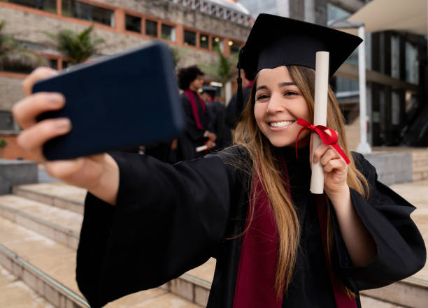 estudiante graduado feliz tomando un selfie - poses para fotos de graduación fotografías e imágenes de stock