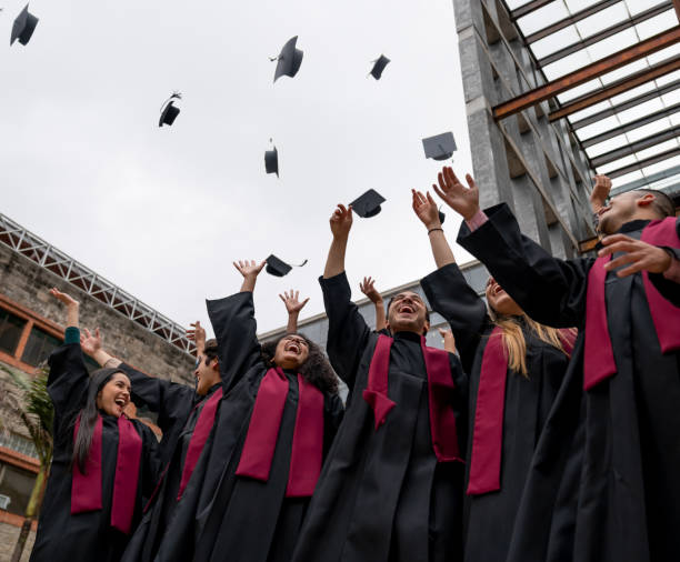istock group of graduating students throwing their mortarboards in the air 1204089359