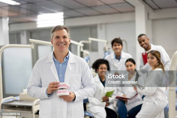 Happy Teacher At Dental School Holding A Prothesis And Smiling Stock Photo - Download Image Now