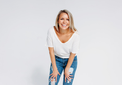 Blonde hair happy woman 35 year plus in white t-shirt and blue jeans isolated on the white background