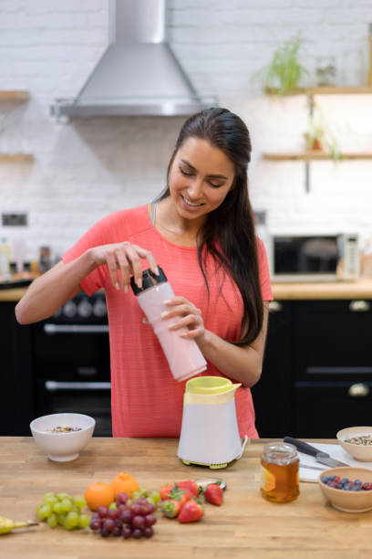 istock Happy woman making a smoothie at home 1204096325