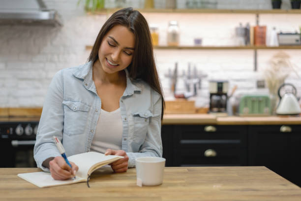 istock Happy woman at home writing on her diary 1204096896