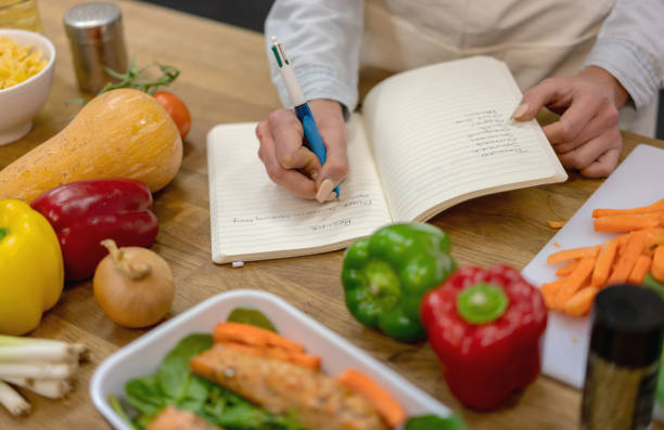 istock Woman at home writing a vegetarian recipe while cooking 1204096898