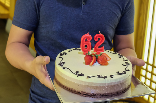 Close up young man carrying a birthday cake in a surprise party