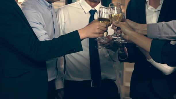成功したビジネスマンは、ボールルームのディナーのごちそうでワインとシャンパンを飲みます。 - party business toast champagne ストックフォトと画像