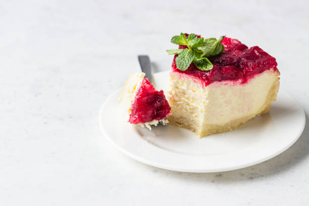 istock Classical New York cheesecake with cranberry sauce, mint and rosemary, light grey stone background. 1204107838