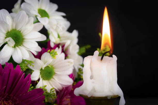 istock Short candle burning in close-up among flowers 1204116319