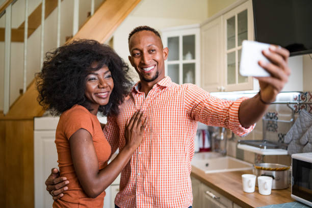 istock Young couple in the kitchen room drinking coffee and taking selfie 1204117368