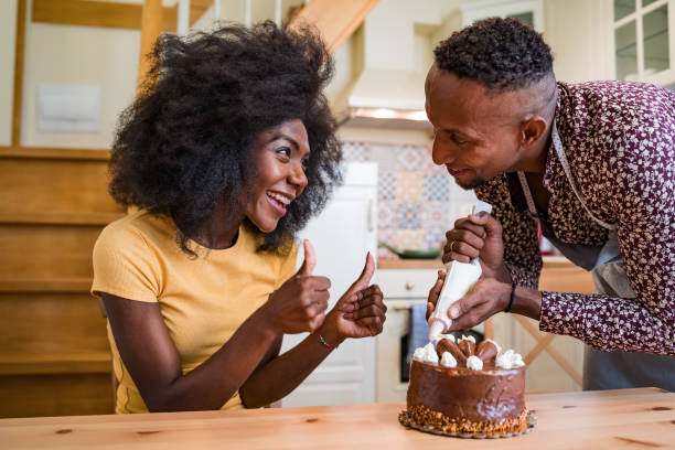 istock Couple in love decorating a cake at home 1204117379