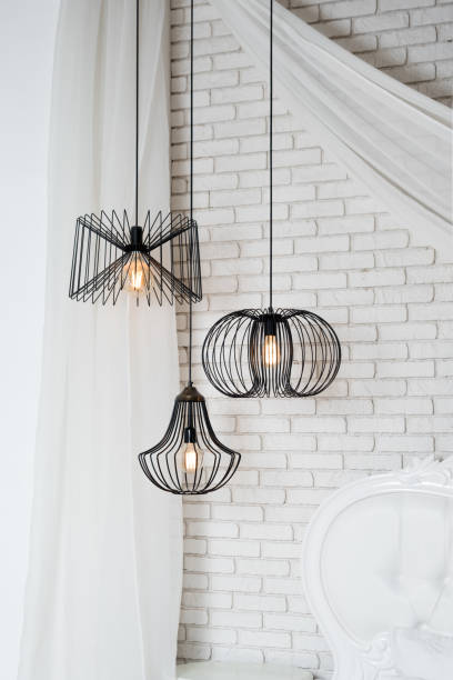 istock Black lamps in light bedroom interior. Three modern black lamps hanging 1204117401