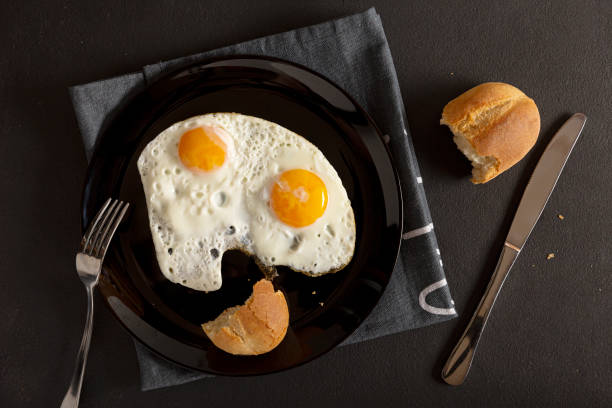 uova servite, pancetta uova, tovaglia grigia, colazione, due fritti - cast iron skillet foto e immagini stock