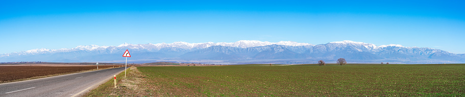 Wide panorama overlooking the road between green farm fields