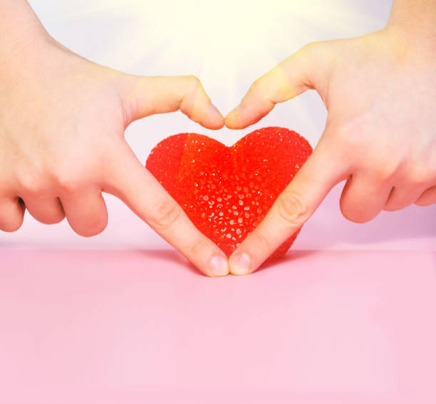 istock Hand heart and red heart shape.Pink background.Sun rays.Sunshine.Copy space for text. 1204120659