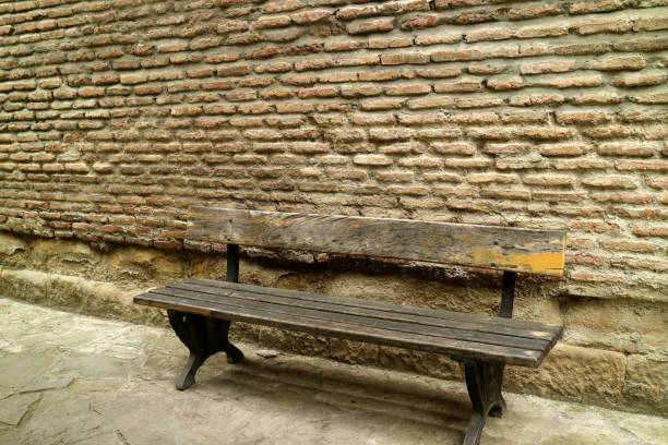 Empty old wooden bench in front of the old brick wall