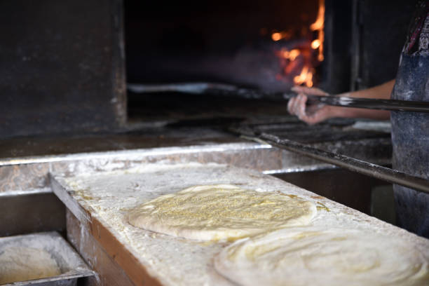 Pastry dough covered with sesame. Bakery owner burns bread in a kiln.