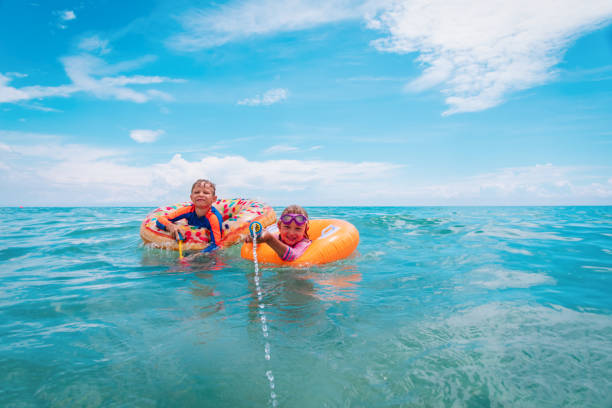 istock happy boy and girl play with water guns while floating on beach 1204129960