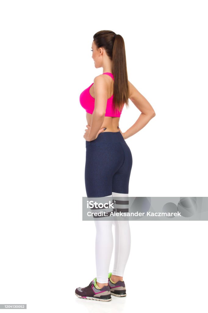 핑크 스포츠 브래지어와 레깅스의 아름다운 젊은 여성은 엉덩이에 손을 들고 서있다 후면 측면 보기 손을 엉덩이에 대기에 대한 스톡 사진  및 기타 이미지 - Istock