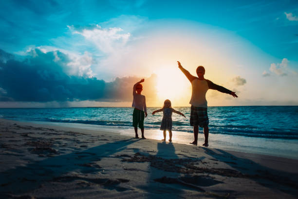 istock father with son and daughter silhouettes play at sunset beach 1204132336