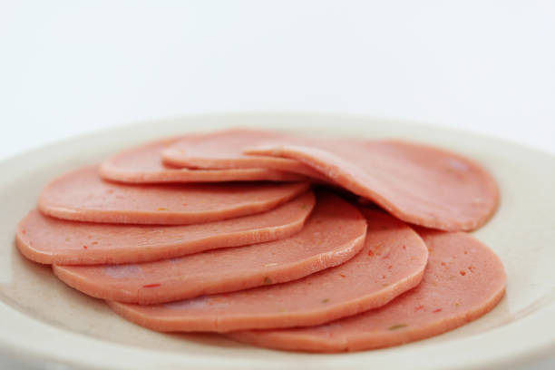 Cooked boiled ham sausage or rolled bologna slices on a white plate.