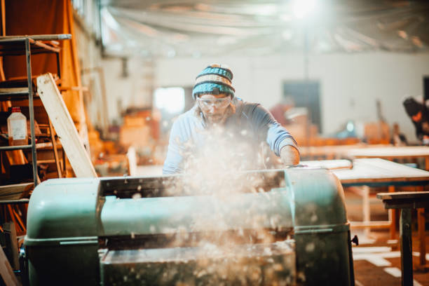istock Woodchips flying into the camera direction from a plank cutting machinery the carpenter is working on 1204143010