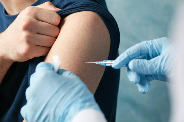 o médico faz um paciente de injeção em fundo azul. proteção coronavírus. saúde e conceito médico - syringe vaccination human hand medical procedure - fotografias e filmes do acervo