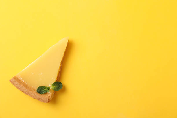 istock Lemon tart slice on yellow background, top view 1204147111