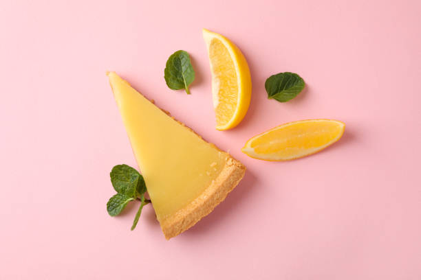 istock Lemon tart slice and lemon slices on pink background, top view 1204149110