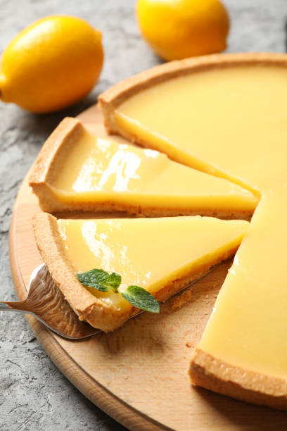 istock Wooden board with lemon tart on grey background, close up 1204149177