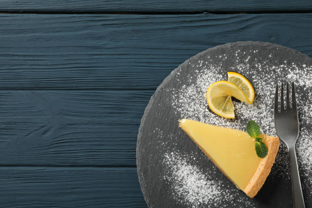 istock Marble tray with lemon tart slice on wooden background, top view 1204149593