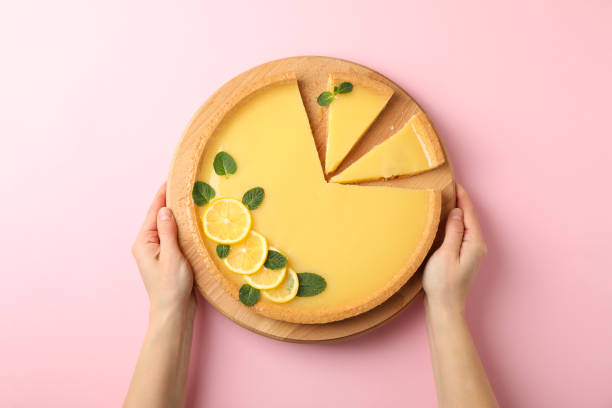 istock Female hands hold board with lemon tart on pink background, top view 1204150288