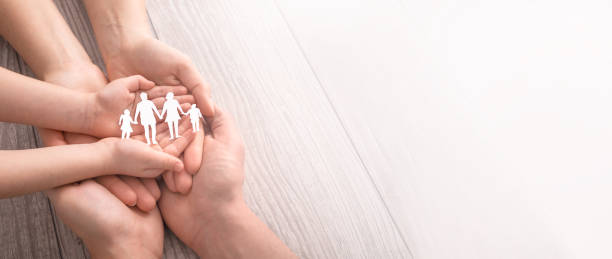istock Family care concept. Hands with paper silhouette on table. 1204150780