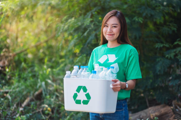 istock woman collecting garbage and holding a recycle bin with plastic bottles 1204152917