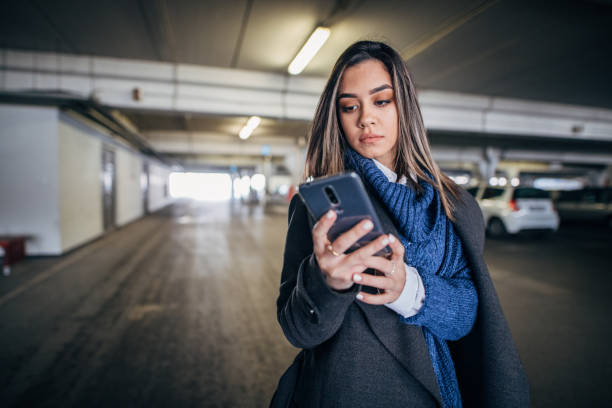 istock Pretty young woman in underground garage using smart phone 1204152936