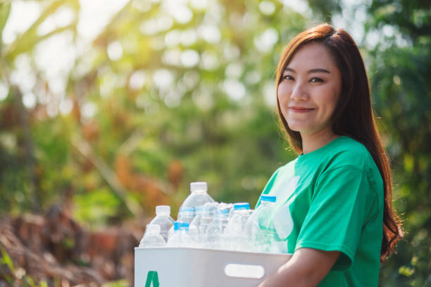 istock woman collecting garbage and holding a recycle bin with plastic bottles 1204152989