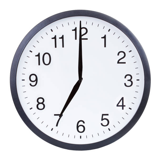 istock Round office clock showing seven o'clock isolated on white background 1204156160
